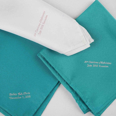 Customized reunion napkins in teal and white, featuring embroidered names and dates.