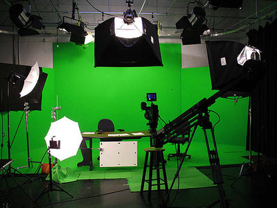 Green screen studio setup with lighting and camera equipment.