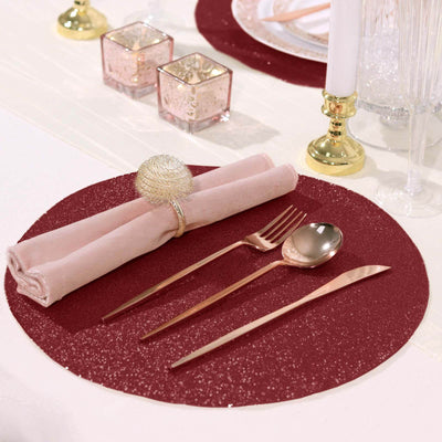 Elegant table setting with burgundy placemat, silver cutlery, and soft pink napkin.
