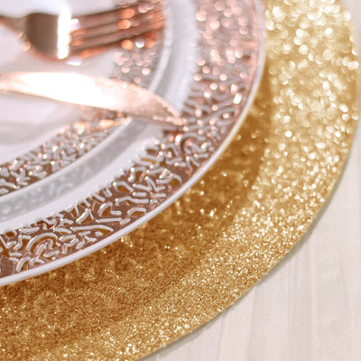 Elegant gold glitter charger plate with intricate white dinnerware on a soft fabric backdrop.