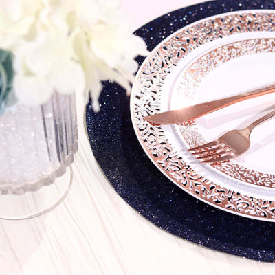 Elegant rose gold cutlery on a decorative plate with a navy glitter placemat.