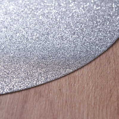 Silver glitter paper texture close-up on wooden surface.