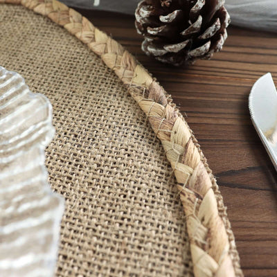 Braided jute placemat with a glass dish and pinecone on wooden table.