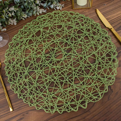Green woven placemat on wooden table with gold utensils.
