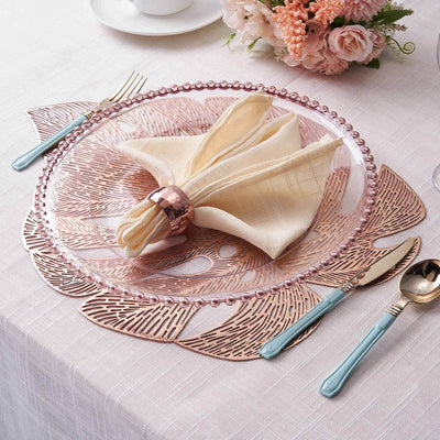 Elegant rose gold charger plate with decorative edges and matching utensils.
