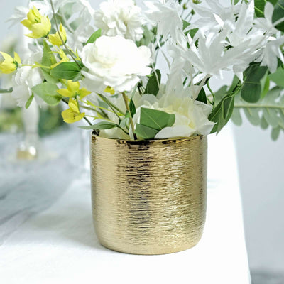 Gold textured vase with white and yellow flowers.