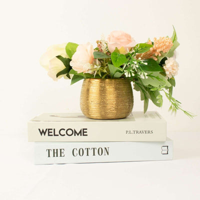 Gold vase with pink flowers on stacked books.