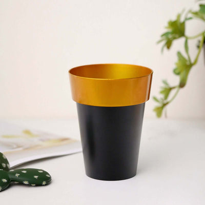 Black and gold cup on a table with a plant and magazine