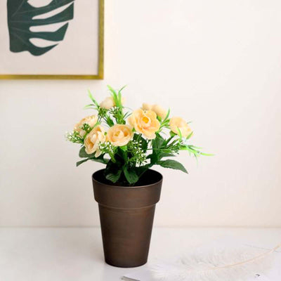 Artificial yellow rose bouquet in a brown pot on a table.