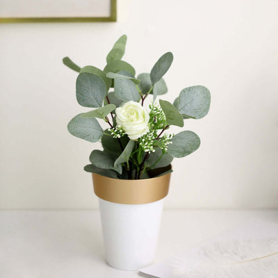 Artificial flower arrangement in a modern white pot with gold trim.