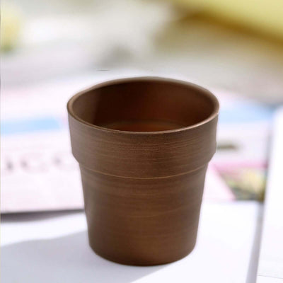 Brown ceramic flower pot on a table.