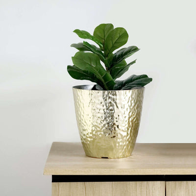 Gold hammered planter with a leafy plant on a wooden surface.