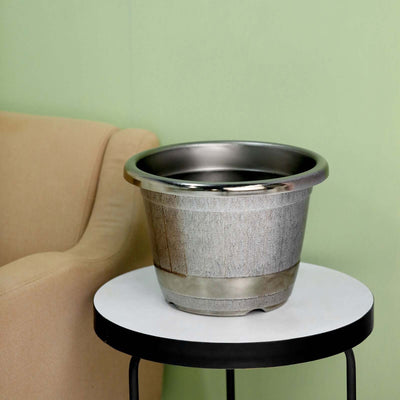 Decorative metal planter on a side table against a green wall.