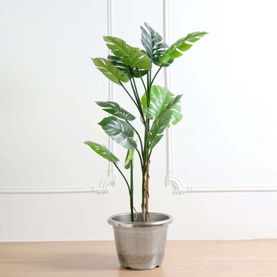 Artificial Monstera plant in a decorative pot on a plain background