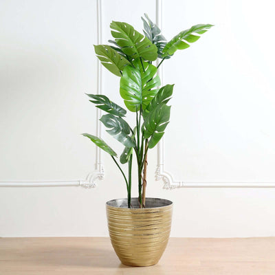 Artificial potted plant with green leaves in a gold textured pot