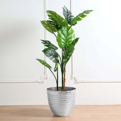 Artificial potted plant with green leaves in a silver pot.