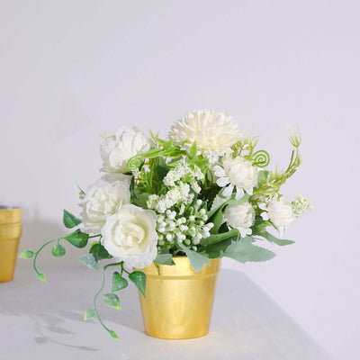 White floral arrangement in a gold pot against a plain backdrop