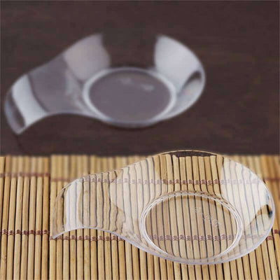Clear glass tea cup saucer on bamboo mat.
