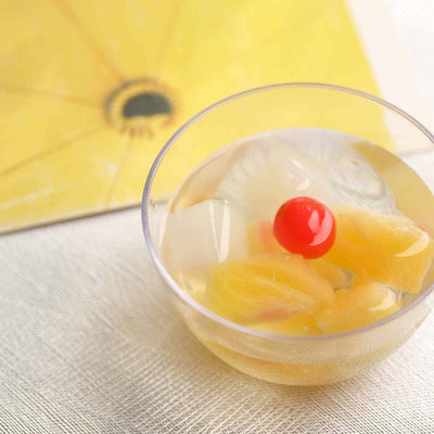 Fruit cocktail in a clear bowl with cherry on top.