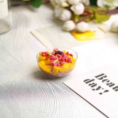Fruit salad in a clear bowl with vibrant mango and berry pieces on a textured surface.
