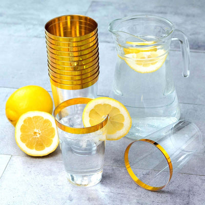Gold-rimmed glasses and pitcher with lemon slices on a countertop.
