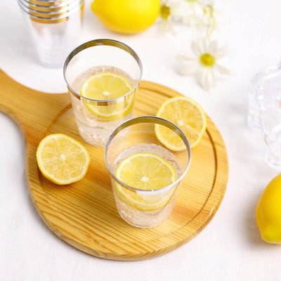 Two glasses of lemonade with lemon slices on a wooden cutting board.