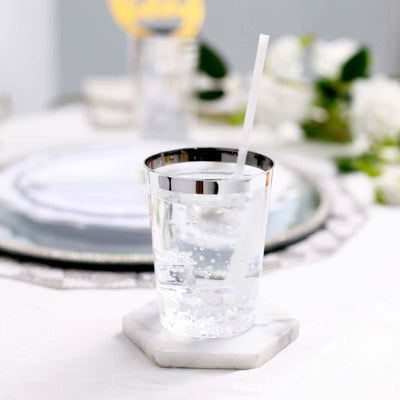 Sparkling water in a stylish glass with a straw on a marble coaster.