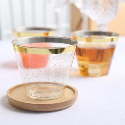 Clear glass cup with gold rim on wooden coaster. Elegant drinkware for stylish settings.