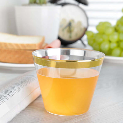 Clear plastic cup with gold stripe filled with orange drink.