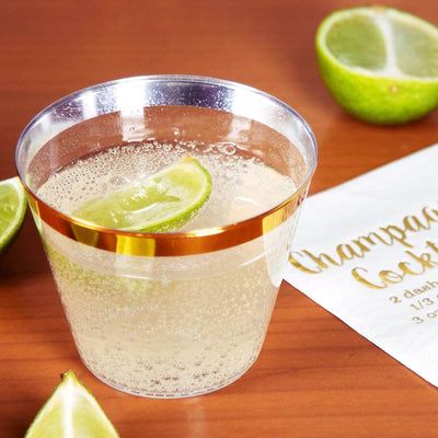 Champagne cocktail in a clear cup with lime slices on a wooden surface.