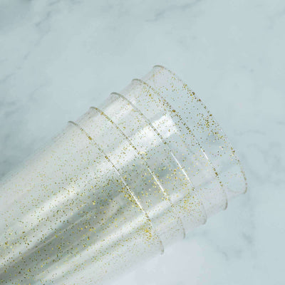 Clear plastic cups with gold glitter accents stacked together.