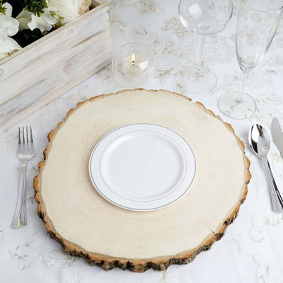 White plate on rustic wood slice with elegant table setting.