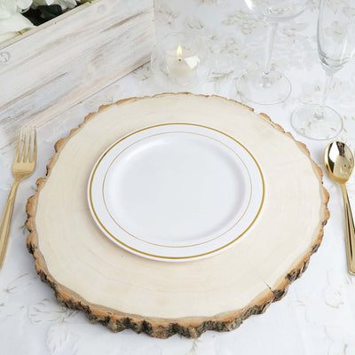 Elegant white plate with gold rim on a rustic wooden table setting.