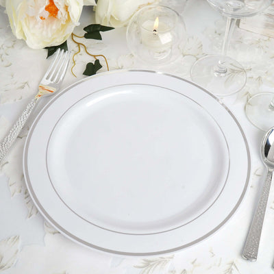 Elegant white dinner plate with silver trim on a decorated table.