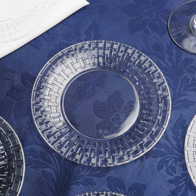 Clear decorative plate on a blue floral tablecloth.