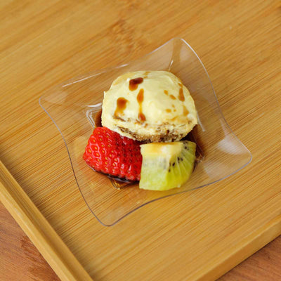 Dessert with ice cream, strawberries, kiwi, and caramel sauce on a wooden surface.