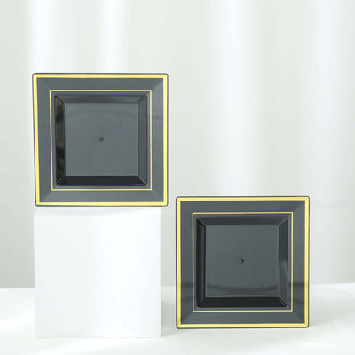 Black square plates with gold trim displayed on a white pedestal.