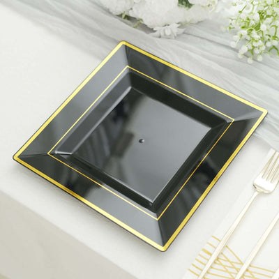 Black square plate with gold trim on a table setting.