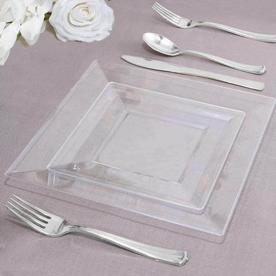 Clear glass dinner plate with elegant silver cutlery on a textured tablecloth.