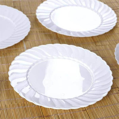 White decorative plates with scalloped edges on a bamboo mat.