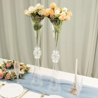 Elegant clear vases with pink and cream roses on a decorated dining table.