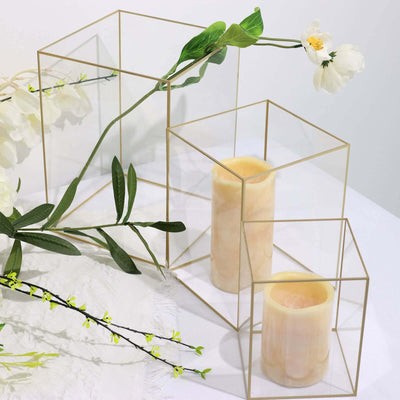 Gold geometric candle holders with decorative foliage.
