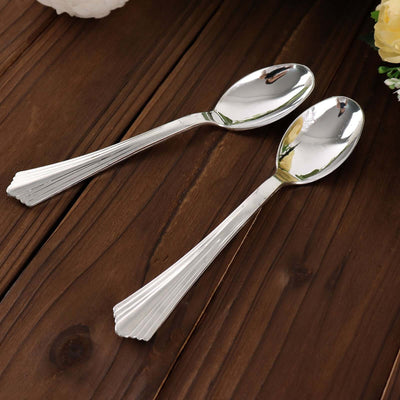 Two elegant silver spoons on a wooden surface.