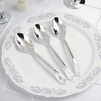 Three elegant silver spoons on a decorative white plate.