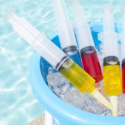 Colorful syringes filled with liquid in a bucket of ice by a pool.