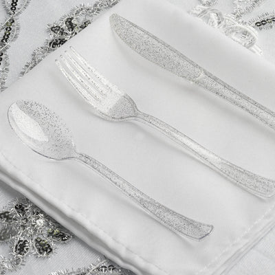 Clear glitter disposable cutlery set on a white napkin.