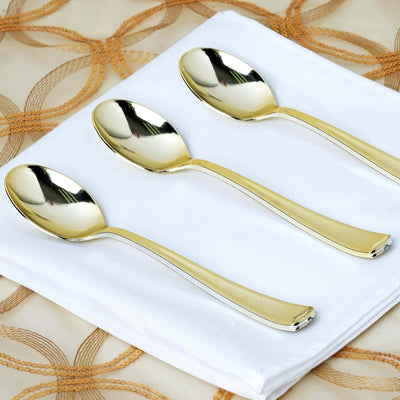 Set of three elegant gold and silver spoons on a white napkin.