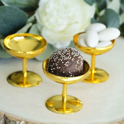 Gold dessert cups with chocolate truffle and white candies on a wooden surface.