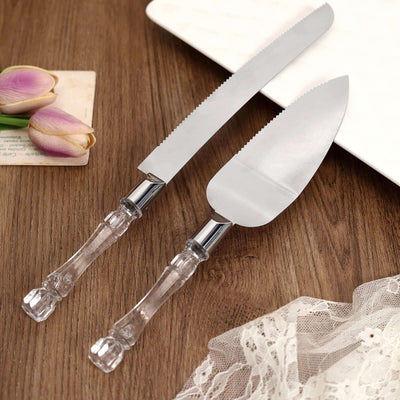 Cake server and knife set with clear handles on a wooden surface.