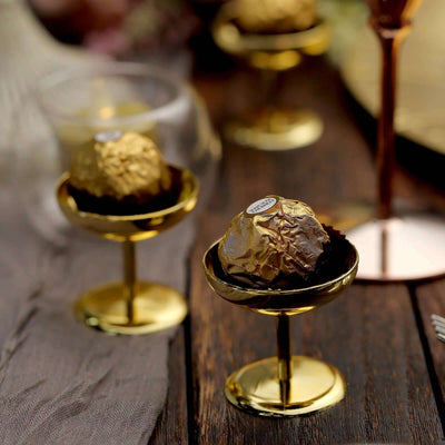 Gold-wrapped chocolate truffles in elegant stands on a table.